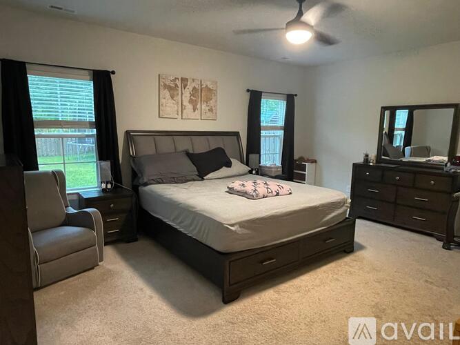 A bedroom with a bed, dresser, and chair.