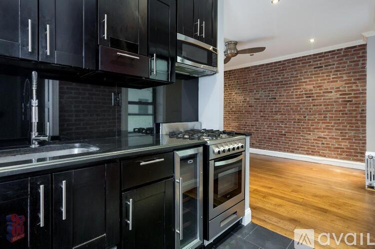 A kitchen with black cabinets and a brick wall.
