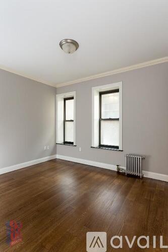 A room with wooden floors and two windows.