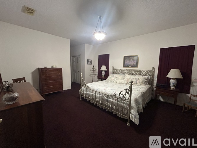 A bedroom with a large bed and a wooden dresser.