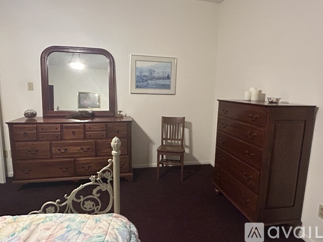 A bedroom with a bed, dresser, and chair.