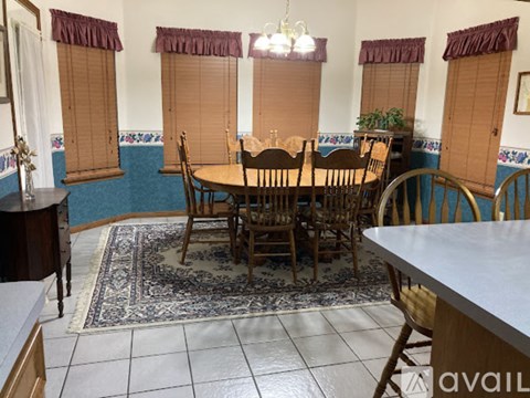 A dining room with a table surrounded by chairs.
