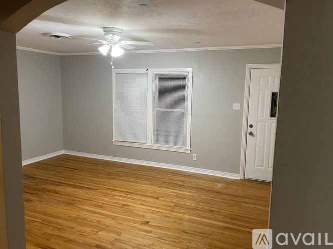 A room with wooden flooring and a window with blinds.