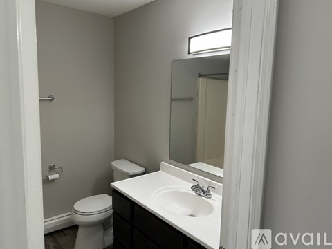 A bathroom with a toilet, sink, and mirror.