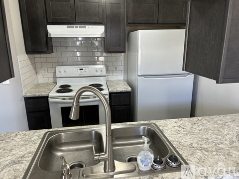 A kitchen with a stove, sink, and refrigerator.