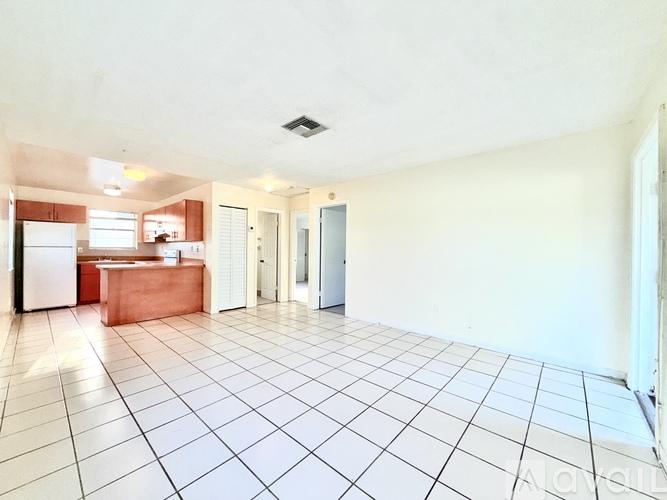 A large empty room with white tiled flooring and white walls.