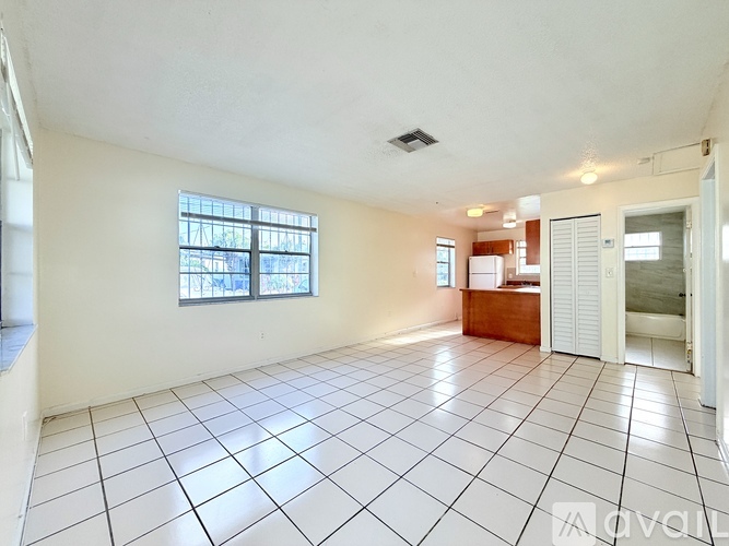 A spacious living room with white tiled flooring and a large window.