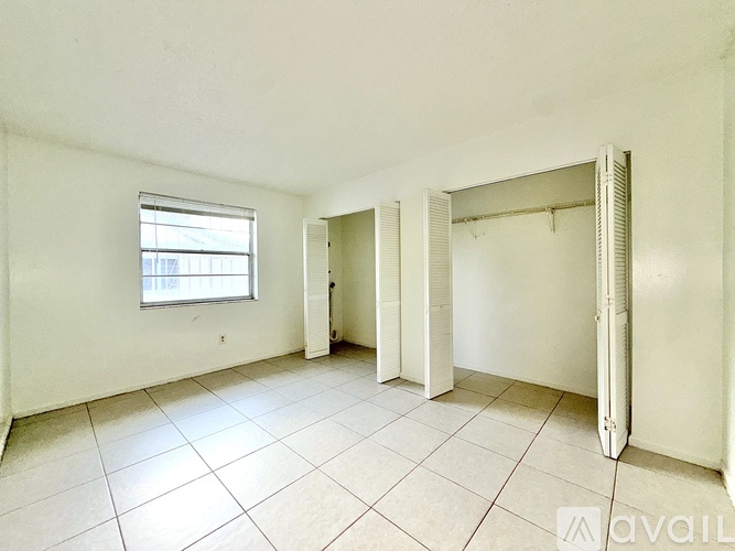 A spacious room with a window and tiled flooring.
