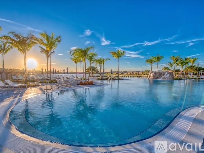 A large outdoor swimming pool surrounded by palm trees and lounge chairs.