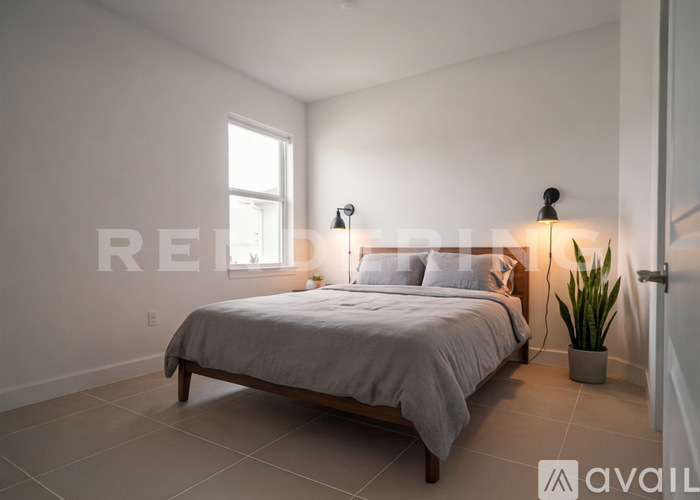 A bedroom with a bed, two lamps, and a plant.