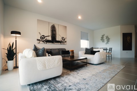 A modern living room with a white sofa, a coffee table, and a large painting of a plane.