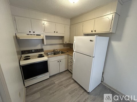 A small kitchen with a white refrigerator, stove, and cabinets.