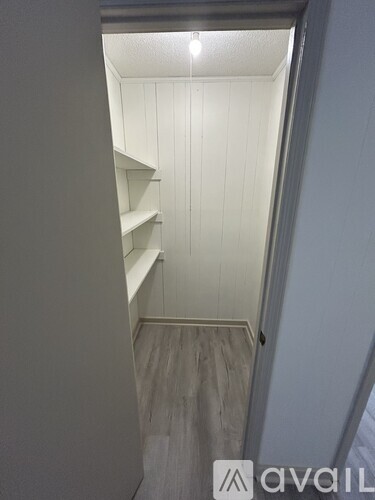 A hallway with a white wall and a wooden floor.