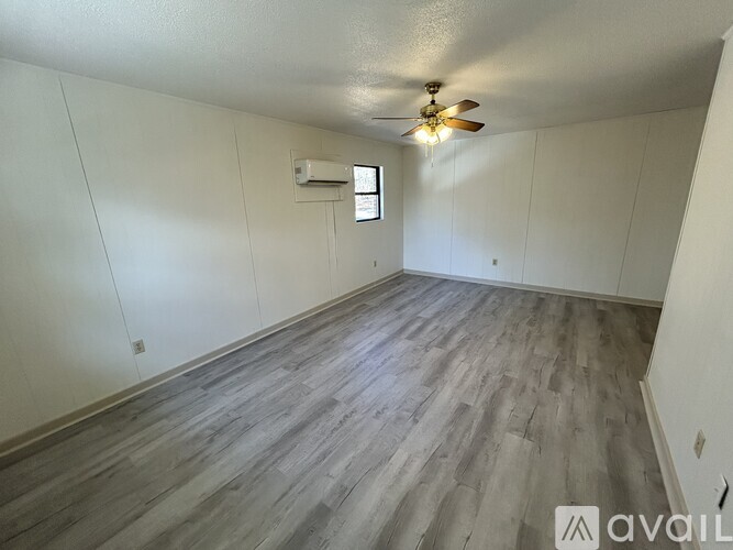 A room with a ceiling fan and a window with blinds.
