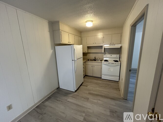 A kitchen with white appliances and wooden floors.