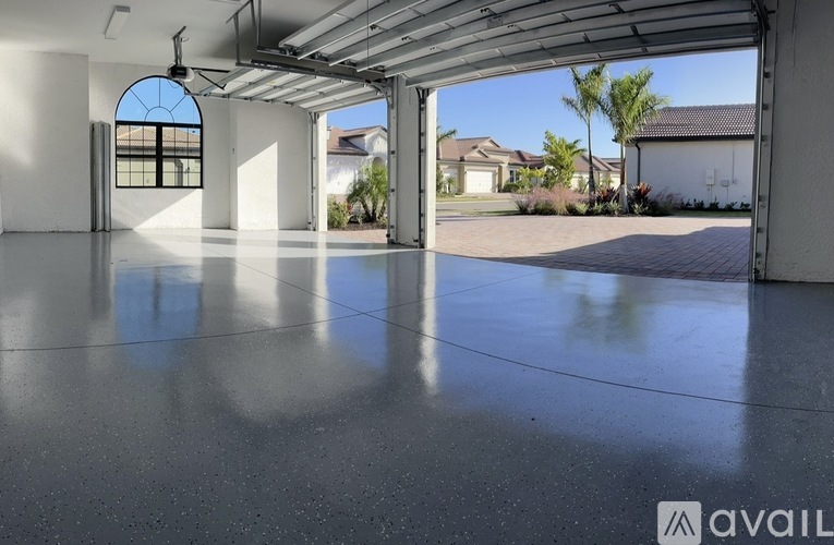 A spacious garage with a large open door leading to a residential area.