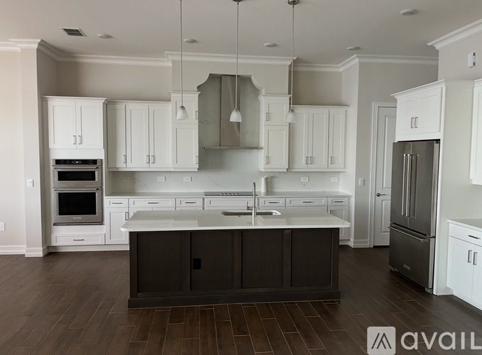 A kitchen with white cabinets and a dark island.
