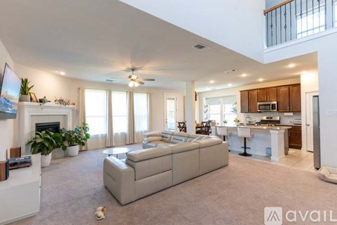A spacious living room with a grey sofa and a fireplace.