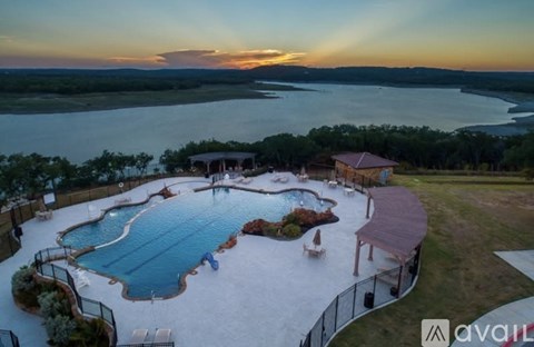 A large outdoor swimming pool surrounded by a fence with a sunset in the background.