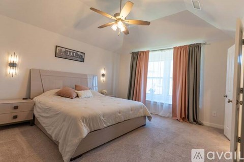 A bedroom with a large bed and a ceiling fan.