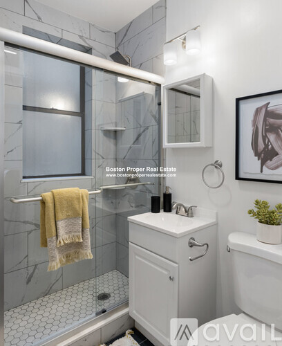 A bathroom with a white sink and a towel hanging on the shower door.