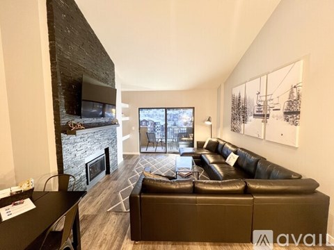 A living room with a black leather couch and a fireplace.