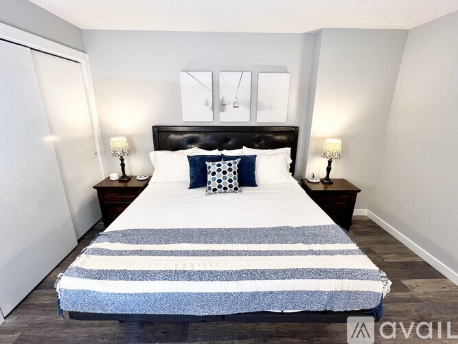 A bedroom with a bed, two lamps, and a nightstand.