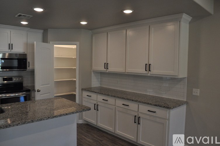 A kitchen with white cabinets and a granite countertop.