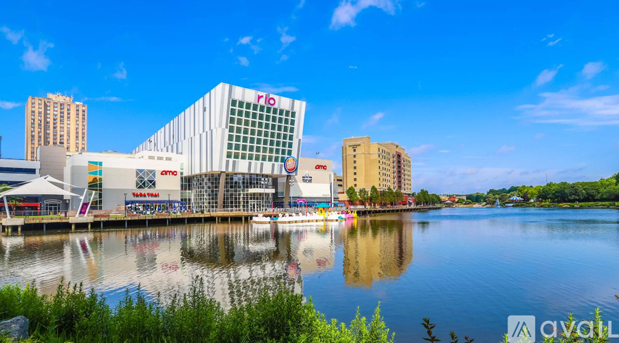 A modern building with the word "rio" on it is reflected in the water in front of it.