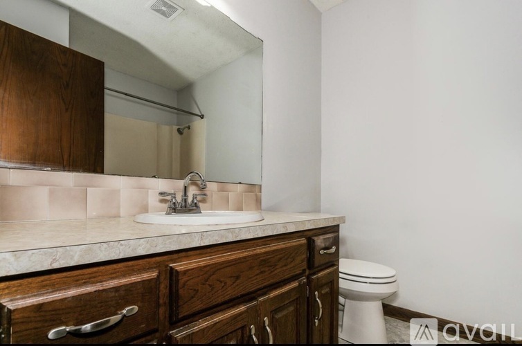 A bathroom with a sink, toilet and mirror.