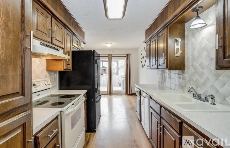 A kitchen with wooden cabinets and a black refrigerator.