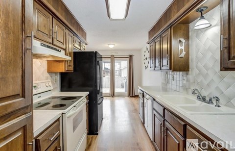 A kitchen with wooden cabinets and a black refrigerator.