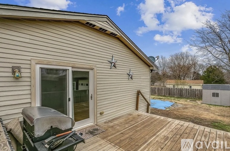 A house with a deck and a BBQ grill.