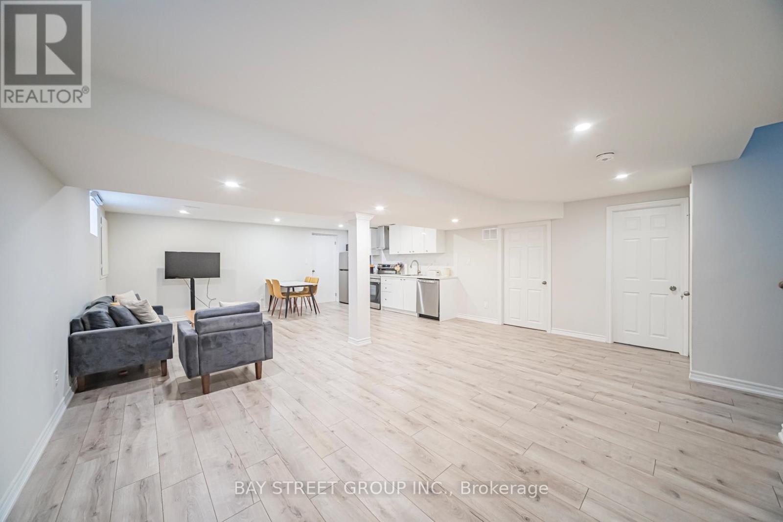 A spacious living room with a grey sofa and wooden flooring.
