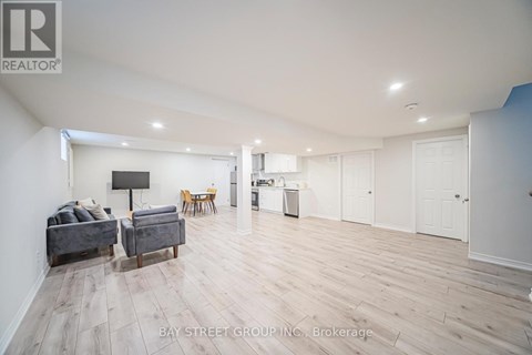 A spacious living room with a grey sofa and wooden flooring.