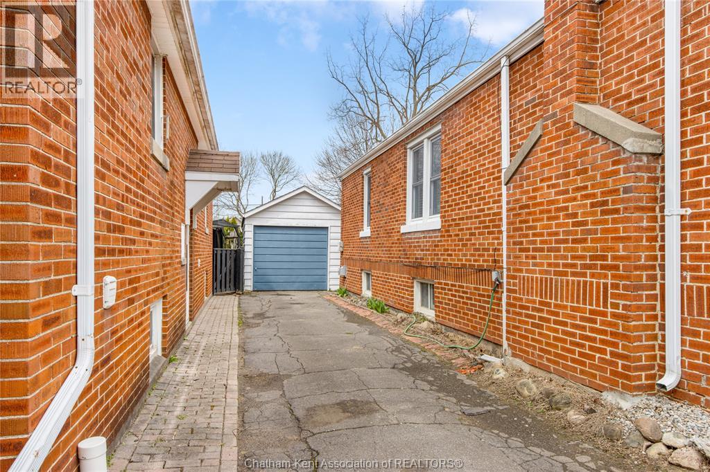 A narrow alley between two red brick buildings with a blue garage door in the distance.