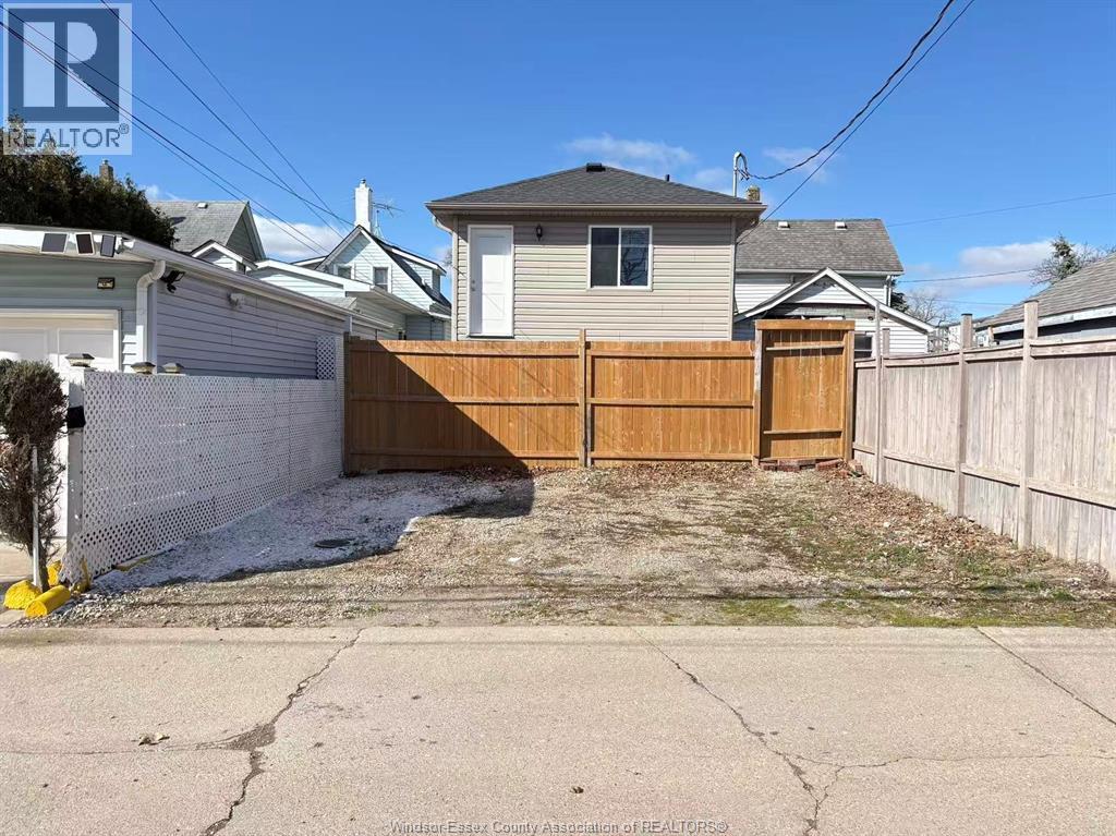 A backyard with a wooden fence and a house in the background.