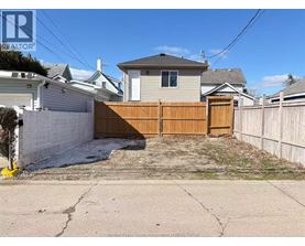 A backyard with a wooden fence and a house in the background.