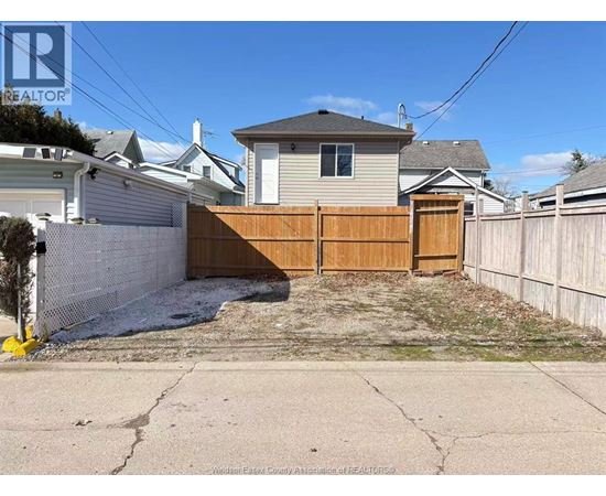 A backyard with a wooden fence and a house in the background.