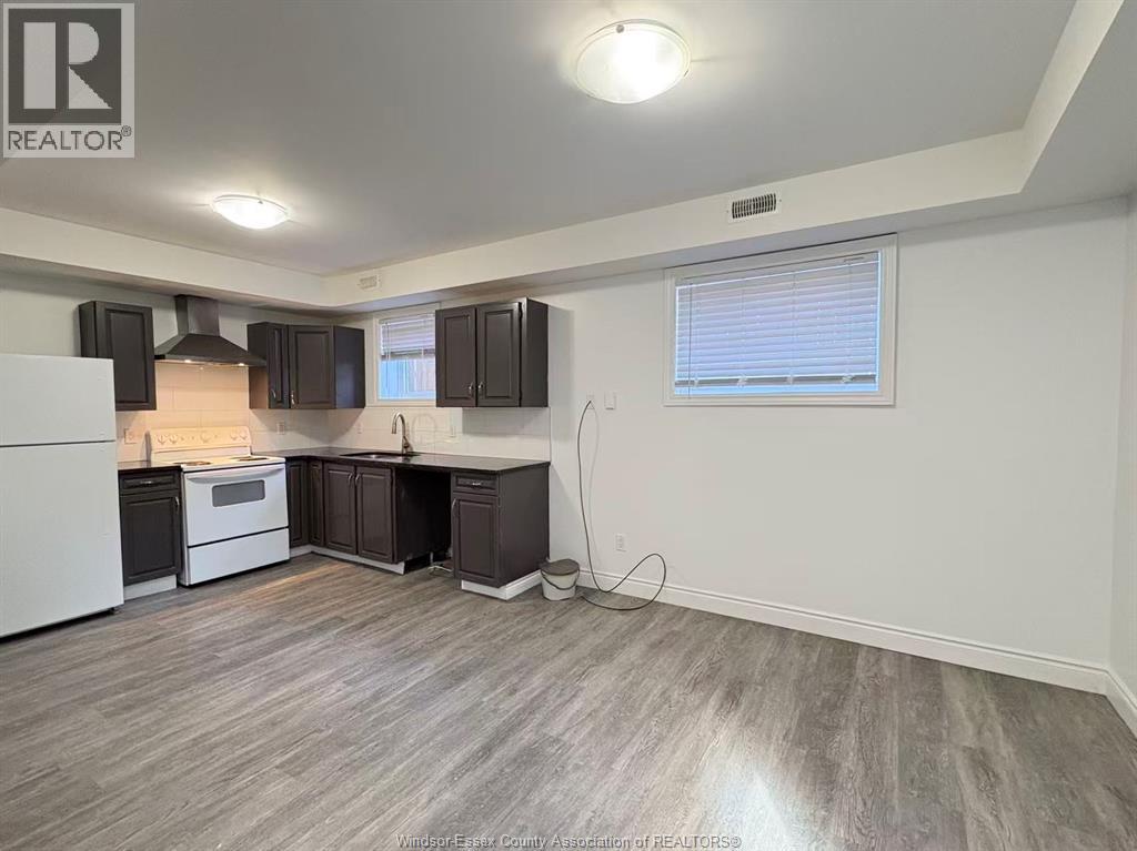 A kitchen with a white refrigerator, black cabinets, and a wooden floor.