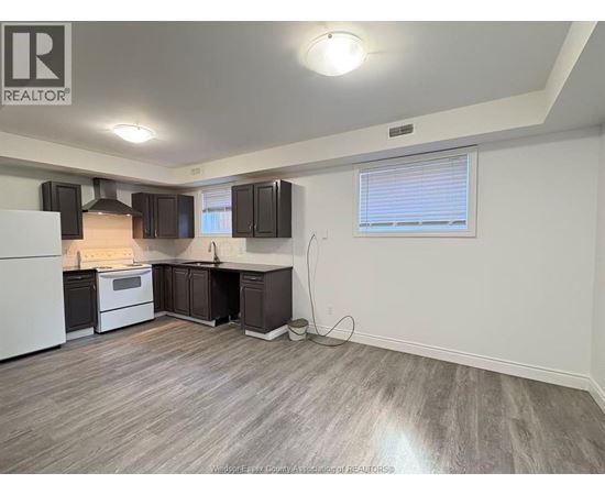 A kitchen with a white refrigerator, black cabinets, and a wooden floor.