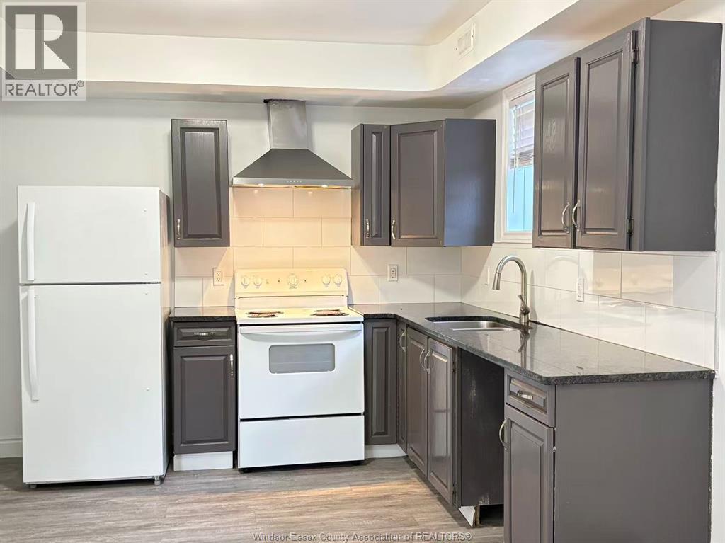 A kitchen with a white refrigerator and black cabinets.