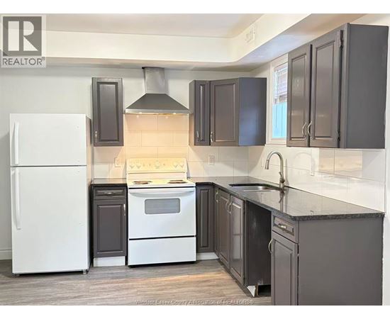 A kitchen with a white refrigerator and black cabinets.