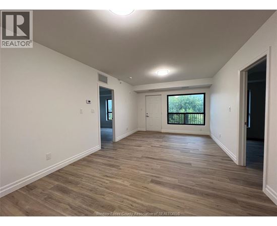 A spacious room with wooden flooring and white walls.
