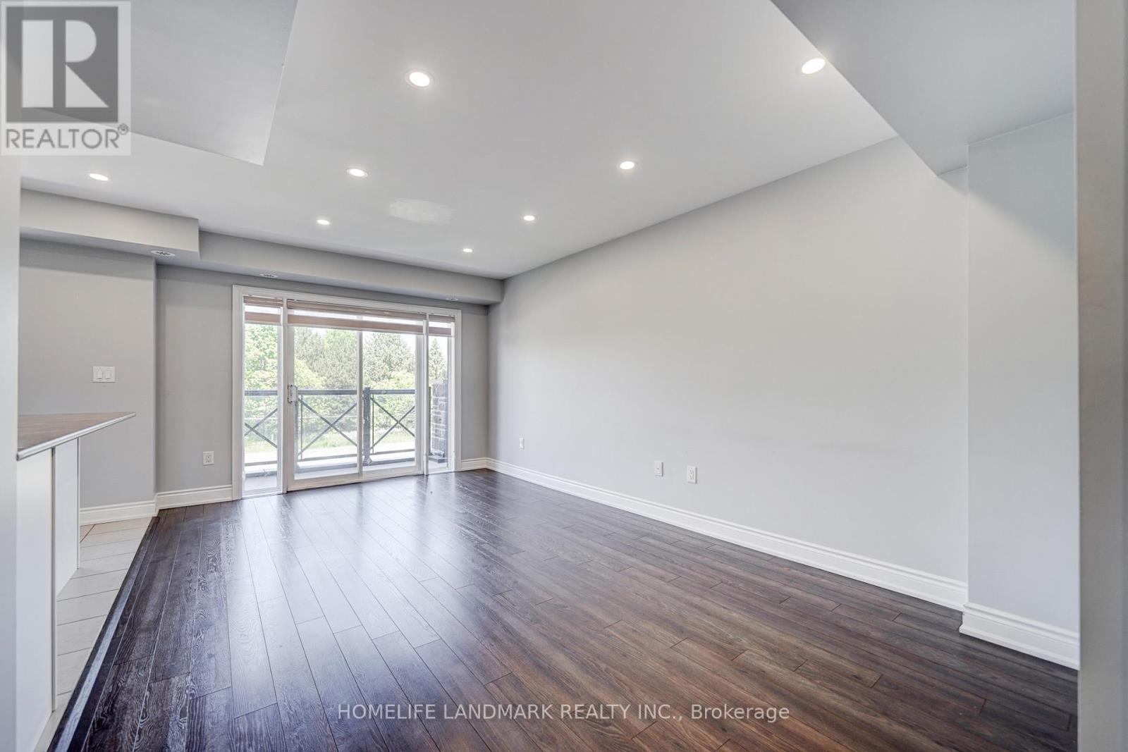 A spacious room with wooden flooring and a sliding glass door leading outside.