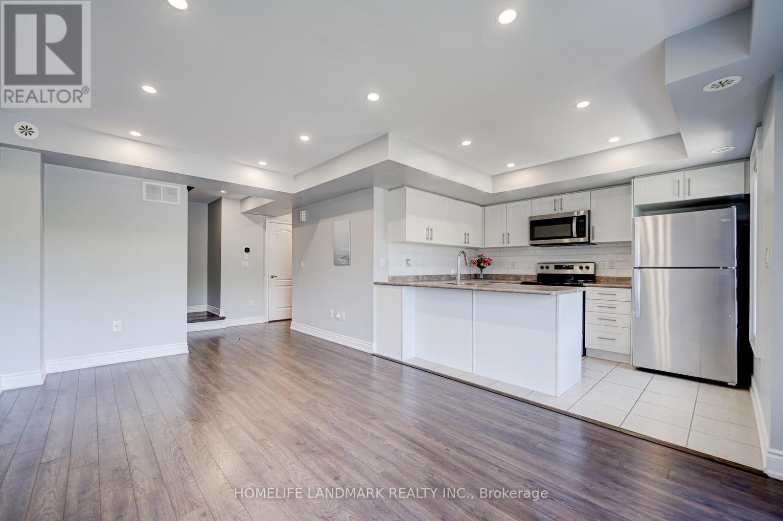 A modern kitchen with white cabinets and a stainless steel refrigerator.