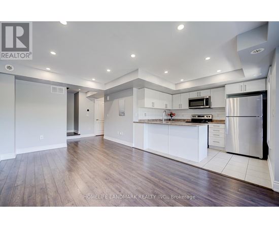 A modern kitchen with white cabinets and a stainless steel refrigerator.