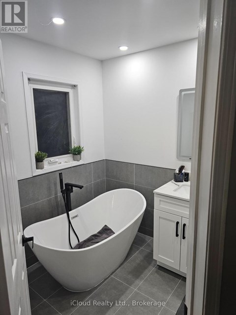 A white bathroom with a tub, sink and window.
