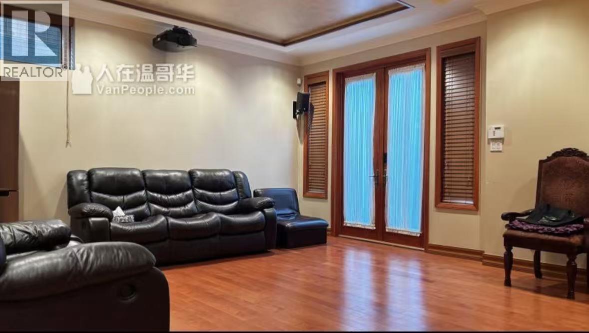 A living room with a black leather couch and a wooden chair.