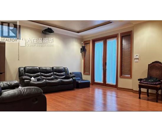 A living room with a black leather couch and a wooden chair.